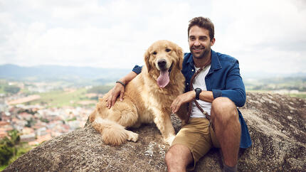 Hund mit Mann auf Berg sitzend
