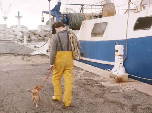 fischer, der seinen hund neben fischerboot geht