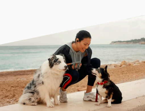 Frau mit zwei Hunden am Strand