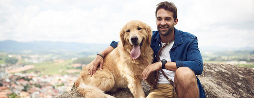 Hund mit Mann auf Berg sitzend