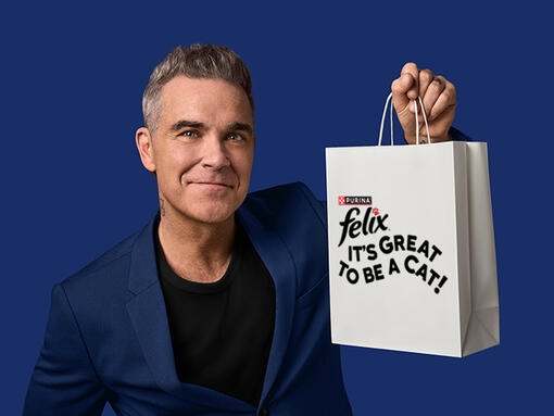 Robbie Williams hält weiße Tasche mit aufgedrucktem FELIX Logo.